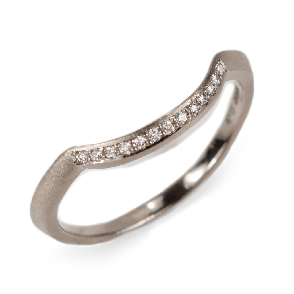 curved eternity wedding band with diamonds on a white background  